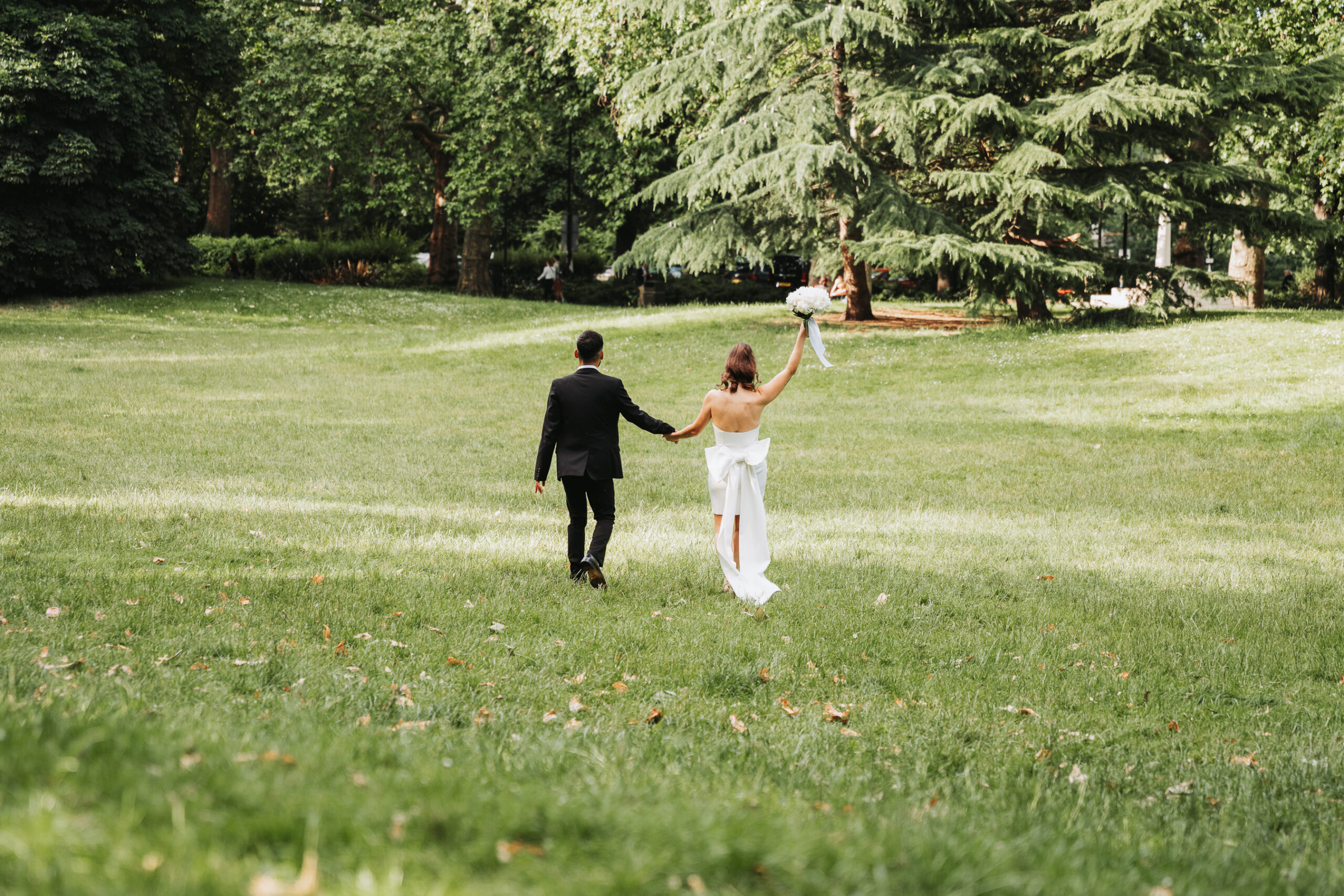 a bride and groom holding hands in a grassy area