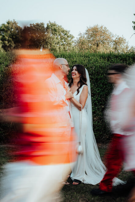 Wedding photo showing a still couple while guests walk through the frame creating motion blur.